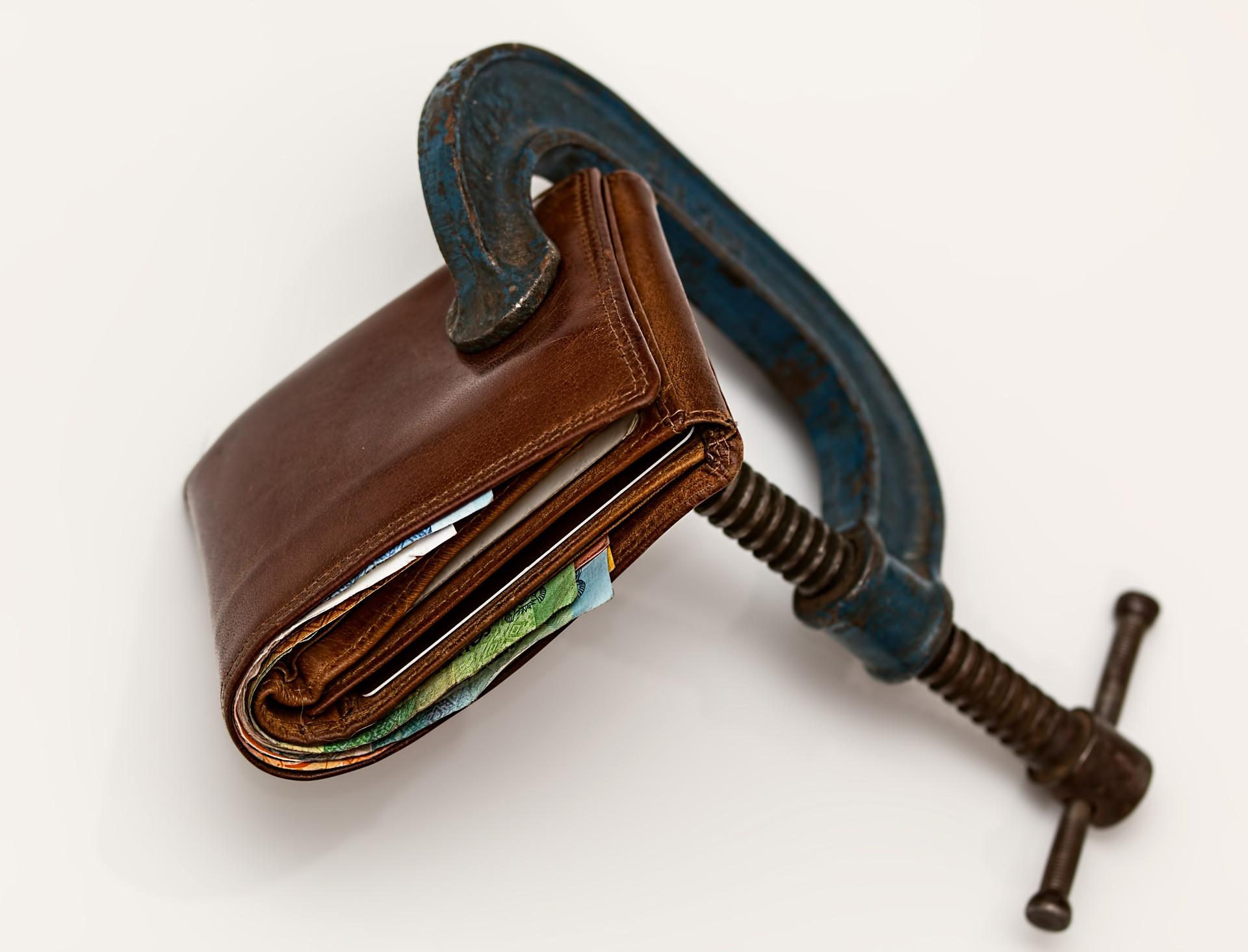 A wallet being compressed with a vice grip