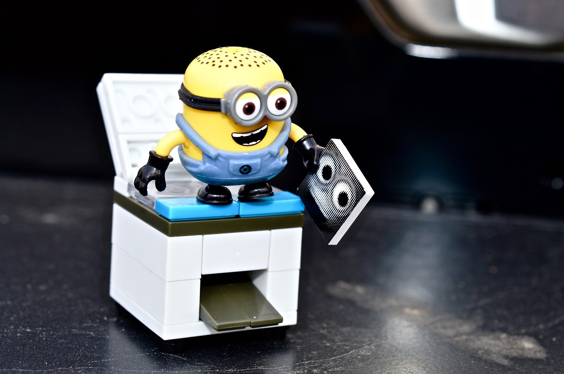 A Lego Minion using a photocopier with a copy of their face in hand.