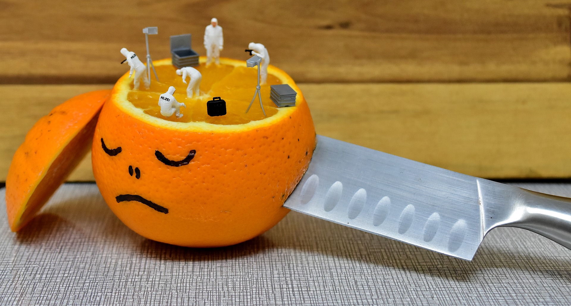 A sad orange with a face drawn on it.  Atop of it are figures doing an what appears to be an investigation.  I assume they need all the hints they can get.